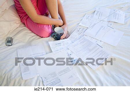 Stock Image - Woman on bed with bills . Fotosearch