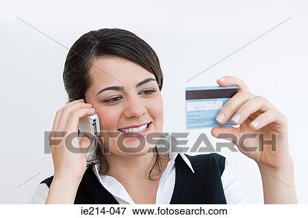 Stock Photo - Woman on cellphone with credit card. Fotosearch