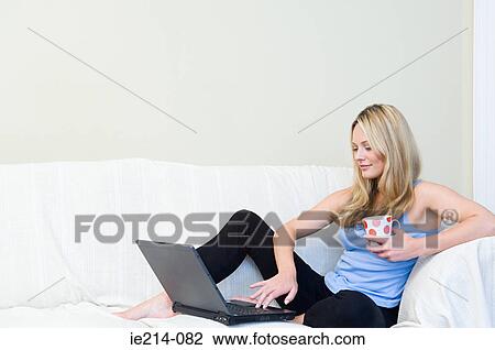 Stock Image - Woman on sofa with laptop. Fotosearch