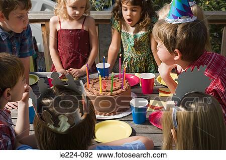 Stock Image - Children blowing out birthday candles. Fotosearch