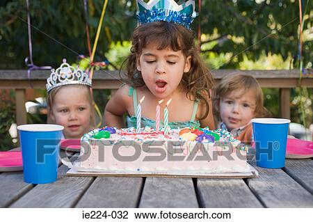 Stock Image - Girl blowing out candles on cake. Fotosearch