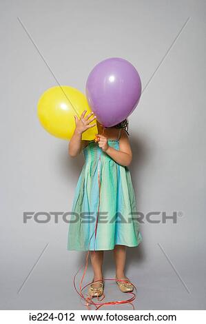 Stock Image - Girl hiding behind balloons. Fotosearch