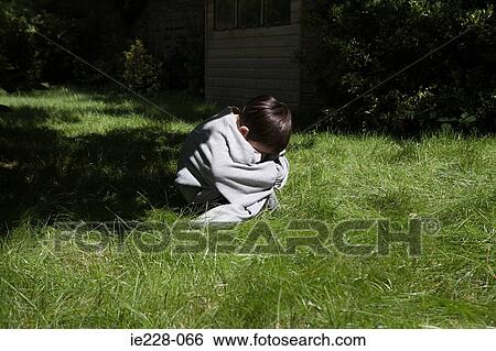 Stock Photograph - Boy cowering in a garden. Fotosearch