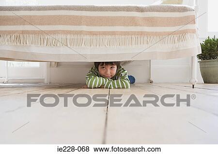 Stock Photo - Boy hiding under a bed. Fotosearch