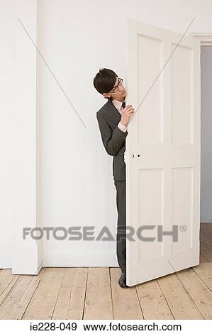 Businessman hiding behind a door View Large Photo Image Stock Photo - Businessman hiding behind a door. Fotosearch
