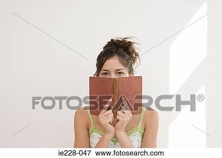 Woman hiding behind a book View Large Photo Image Stock Photo - Woman hiding behind a book. Fotosearch
