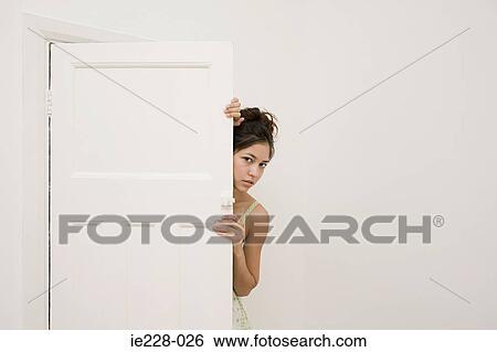 Woman hiding behind a door View Large Photo Image Stock Photograph - Woman hiding behind a door. Fotosearch