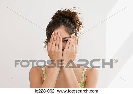 Stock Image - Woman peering through hands. Fotosearch