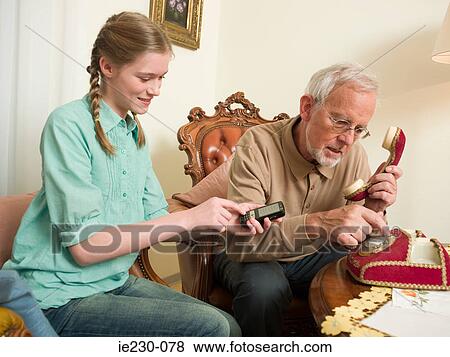 Grandfather and granddaughter using telephones View Large Photo Image Stock Photo - Grandfather and granddaughter using telephones. Fotosearch
