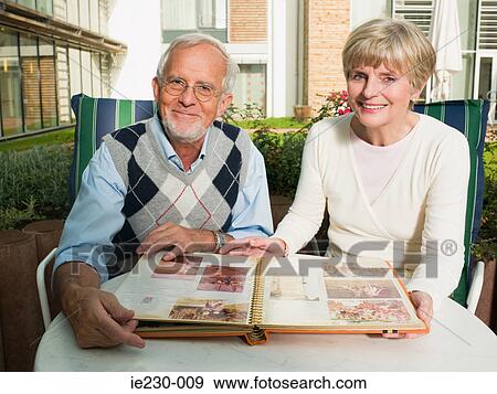Senior couple looking at a photo album View Large Photo Image Stock Photo - Senior couple looking at a photo album. Fotosearch