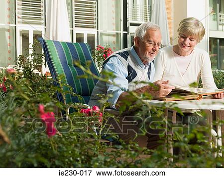 Senior couple looking at a photo album View Large Photo Image Stock Photo - Senior couple looking at a photo album. Fotosearch