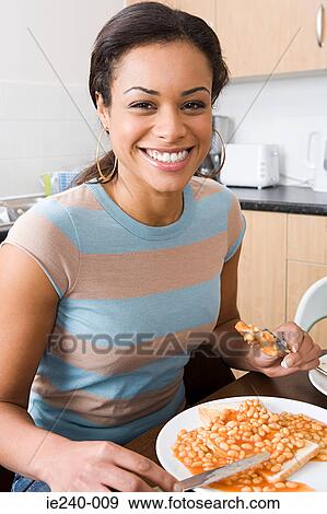 Stock Photo - Young woman eating beans on toast. Fotosearch