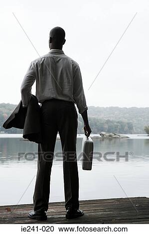 Stock Image - A businessman holding a jacket and a briefcase. Fotosearch