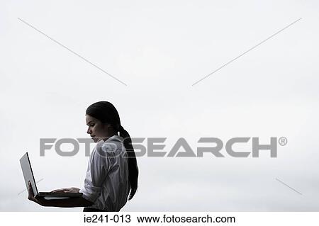 Stock Image - A businesswoman holding a laptop. Fotosearch