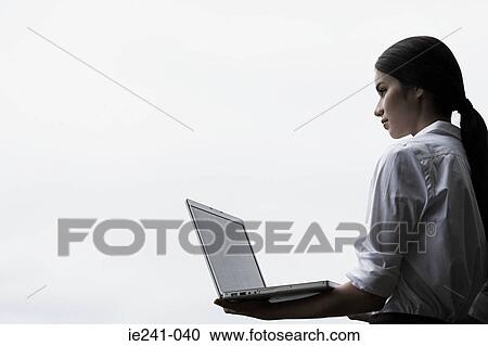 A businesswoman holding a laptop View Large Photo Image Stock Image - A businesswoman holding a laptop. Fotosearch