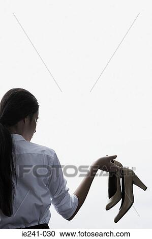 A businesswoman holding high heeled shoes View Large Photo Image Stock Image - A businesswoman holding high heeled shoes. Fotosearch