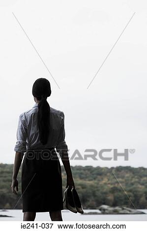 Stock Photo - A businesswoman holding high heeled shoes. Fotosearch