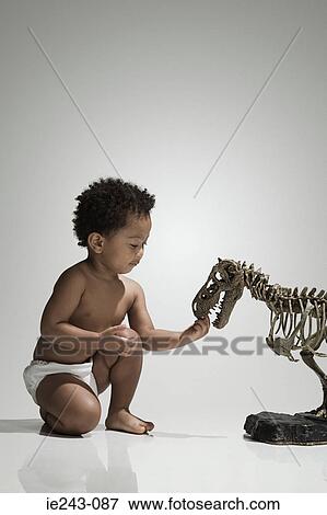 Boy playing with a dinosaur skeleton View Large Photo Image Stock Photo - Boy playing with a dinosaur skeleton. Fotosearch