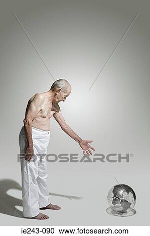 Stock Image - Elderly man looking at a globe. Fotosearch