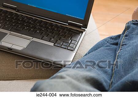 Picture - A person in a lounge with their laptop. Fotosearch