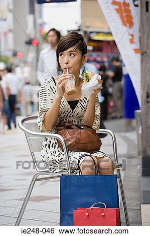 A woman having a drink and a sandwich View Large Photo Image Stock Photograph - A woman having a drink and a sandwich. Fotosearch