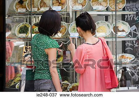 Friends looking in a restaurant window View Large Photo Image Stock Photo - Friends looking in a restaurant window. Fotosearch