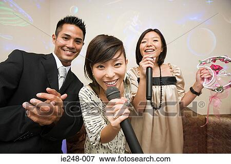 Stock Photo - Friends singing karaoke. Fotosearch