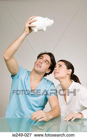 Couple looking in piggy bank View Large Photo Image Stock Photo - Couple looking in piggy bank. Fotosearch