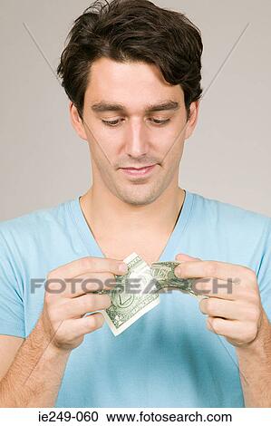 Stock Image - Man ripping a dollar. Fotosearch