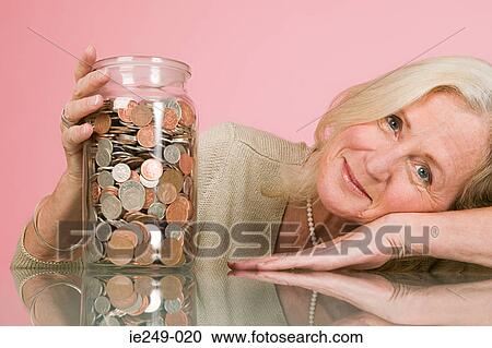 Woman with coins in a jar View Large Photo Image Stock Image - Woman with coins in a jar. Fotosearch