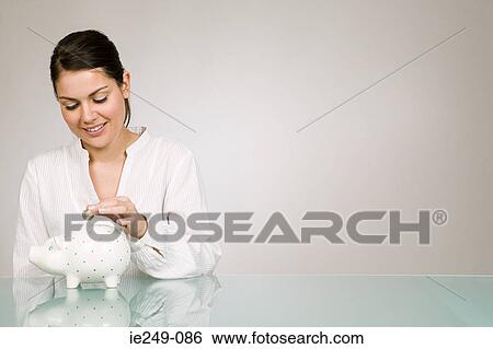 Stock Photograph - Young woman with piggy bank. Fotosearch
