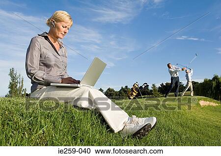 A businesswoman using a laptop on a golf course View Large Photo Image Stock Image - A businesswoman using a laptop on a golf course. Fotosearch