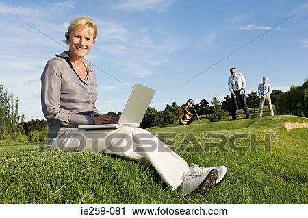 A businesswoman using a laptop on a golf course View Large Photo Image Stock Image - A businesswoman using a laptop on a golf course. Fotosearch