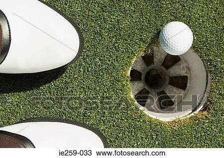 A golf ball on the edge of a hole View Large Photo Image Stock Image - A golf ball on the edge of a hole. Fotosearch