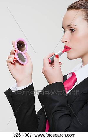 Woman in suit applying lipstick View Large Photo Image Stock Photo - Woman in suit applying lipstick. Fotosearch