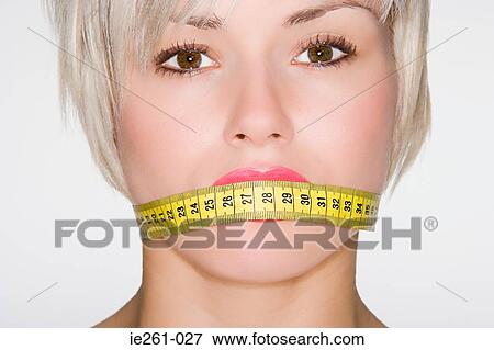 Woman with tape measure over her mouth View Large Photo Image Stock Photo - Woman with tape measure over her mouth. Fotosearch
