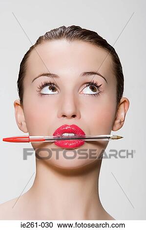 Young woman with pen in her mouth View Large Photo Image Stock Image - Young woman with pen in her mouth. Fotosearch