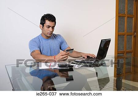 Stock Photo - A man sorting his finances on a laptop. Fotosearch
