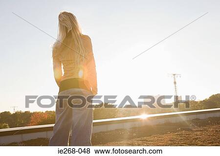 Young woman looking toward the sun View Large Photo Image Stock Photo - Young woman looking toward the sun. Fotosearch
