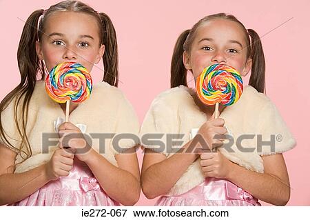 Stock Photo - Twin girls with lollipops. Fotosearch