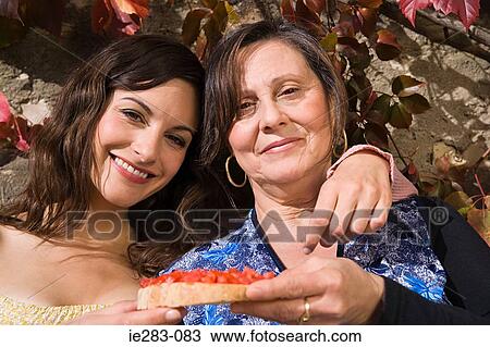 Stock Image - Mother and daughter holding a slice of bruschetta. Fotosearch