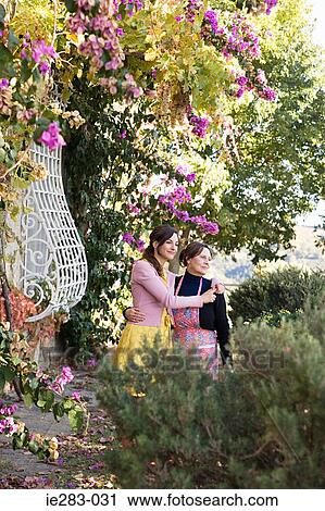 Mother and daughter hugging by plants View Large Photo Image Stock Image - Mother and daughter hugging by plants. Fotosearch