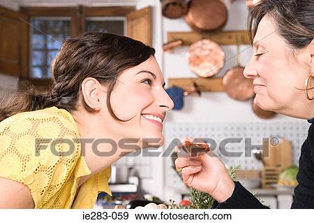 Mother and daughter sampling food View Large Photo Image Stock Photo - Mother and daughter sampling food. Fotosearch