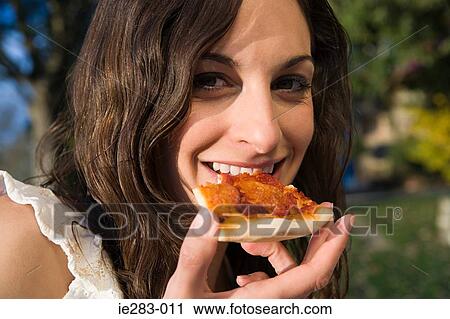 Stock Image - Woman eating a slice of pizza. Fotosearch