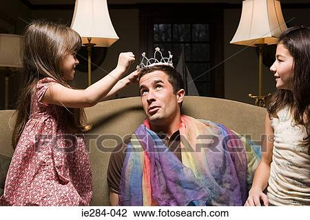 Stock Image - A father and his daughters playing fancy dress. Fotosearch