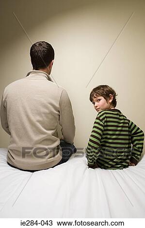 A father and son sat on a bed View Large Photo Image Stock Image - A father and son sat on a bed. Fotosearch