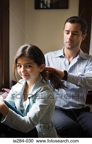 Stock Image - A father styling his daughters hair. Fotosearch
