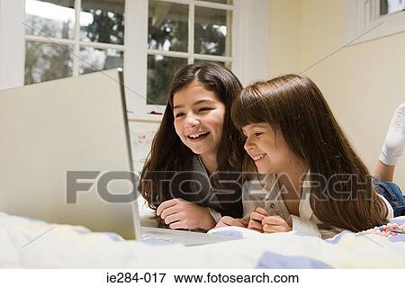 Stock Photo - Sisters using a laptop. Fotosearch