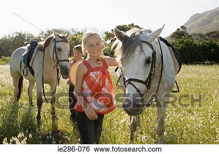 Stock Photograph - A boy and girl with horses. Fotosearch