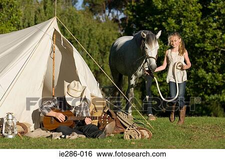 A boy playing a guitar and a girl walking a horse View Large Photo Image Stock Photograph - A boy playing a guitar and a girl walking a horse. Fotosearch